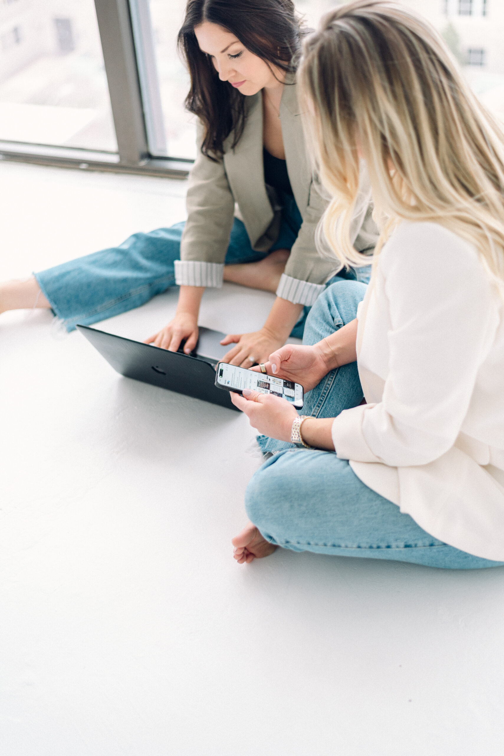 Luxury travel advisor team collaborating around a laptop, reviewing client itineraries in a bright, modern workspace